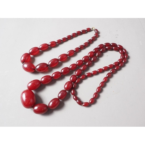 191 - A cherry amber Bakelite bead necklace, the largest oval bead, 34mm long, 71.6g gross, and another si... 