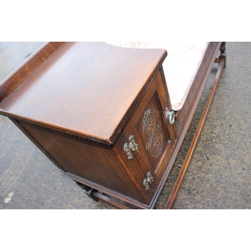 348 - A carved oak window seat, fitted two cupboards, on turned and stretchered supports