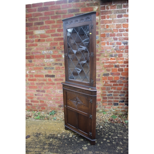 351 - An oak floor standing corner cupboard, fitted leaded glazed door over single carved door, 27