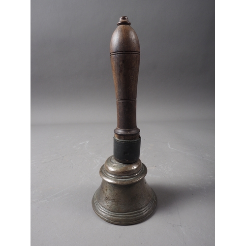 104 - An early 19th century Indian bell metal hand bell with turned hardwood handle, 7 1/2