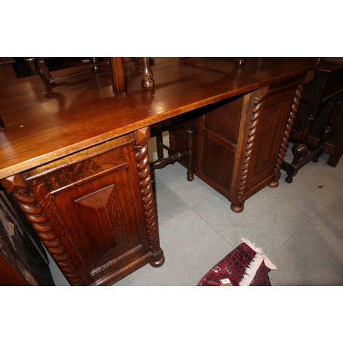 353 - An oak twin pedestal desk, fitted drawers and cupboards with split barley twist pilasters, on bun fe... 