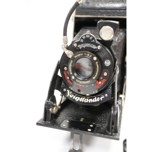 137 - A Voigtlander vest pocket camera and a Kodak camera, a brass preserve pan, a leather chest strap wit... 