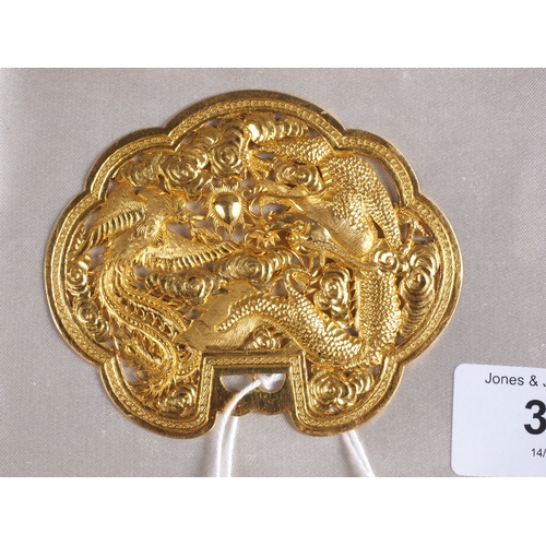 338 - A Chinese yellow metal cloud-shaped pendant with pierced and engraved decoration of two dragons and ... 