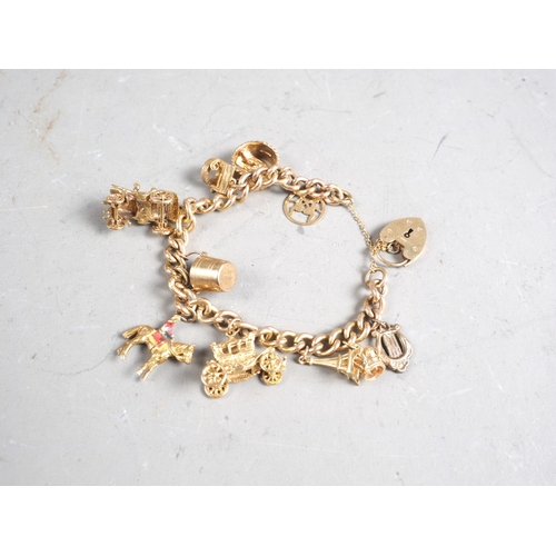 360 - A 9ct gold charm bracelet with eleven charms, including stage coach, wedding ring, wishing well and ... 