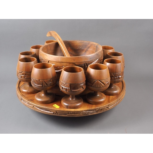 128 - A turned wood punch bowl and ladle, twelve matching goblets and a matching lazy Susan