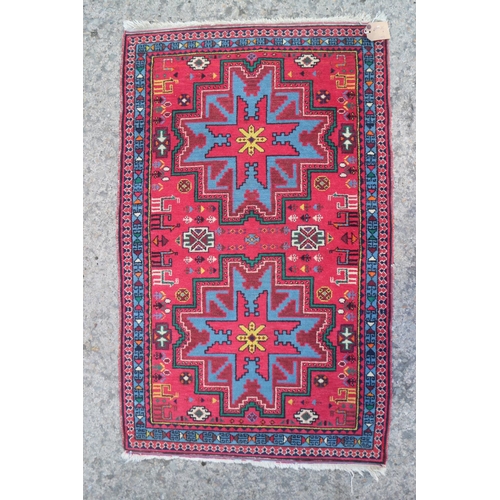 615 - A Kazak rug with two blue and red star medallions, on a red ground with animals and flowers, 30