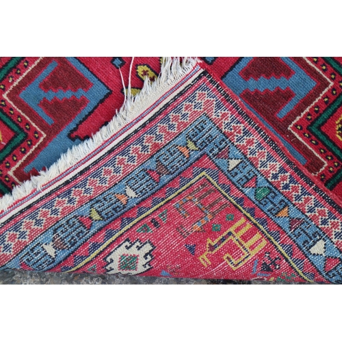 615 - A Kazak rug with two blue and red star medallions, on a red ground with animals and flowers, 30