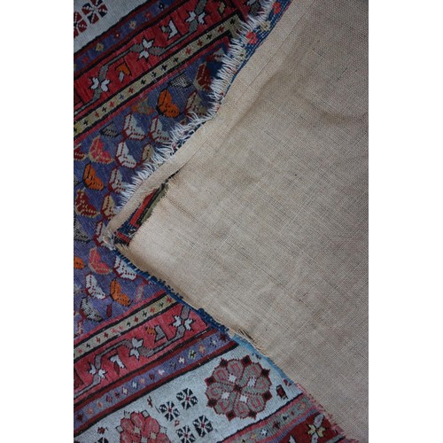 623 - An antique Caucasian rug with floral centre on a purple ground, 88