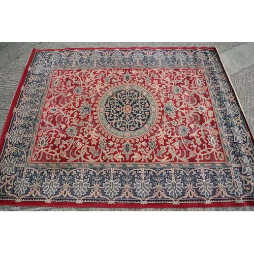 619 - A machine-made woollen carpet of traditional Persian design with foliate motifs, on a crimson ground... 