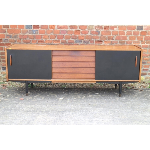 539 - A 1960s teak and ebonised panel sliding door sideboard, fitted five centre drawers, on ebonised turn... 