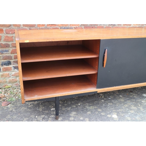 539 - A 1960s teak and ebonised panel sliding door sideboard, fitted five centre drawers, on ebonised turn... 