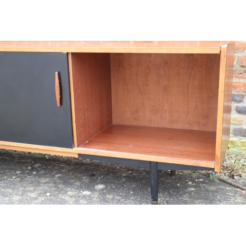 539 - A 1960s teak and ebonised panel sliding door sideboard, fitted five centre drawers, on ebonised turn... 