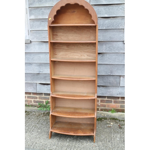 542 - A 1930s oak bowfront arch top waterfall open bookcase, on panel end supports, 23