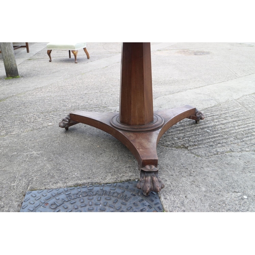 415 - A mid Victorian mahogany circular tilt top dining table, on faceted column, triform base and lion pa... 