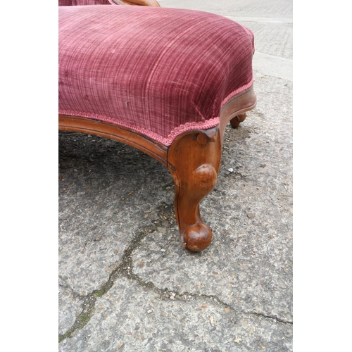 438 - A late Victorian carved walnut showframe chaise longue, upholstered in a claret velour, on cabriole ... 