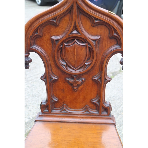 460 - A 19th century carved oak hall chair with Gothic blind fret back and panel seat, on turned supports