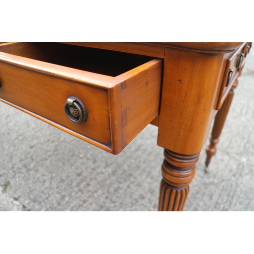 514 - A walnut writing desk with tooled lined top, fitted three drawers, on reeded and castored supports