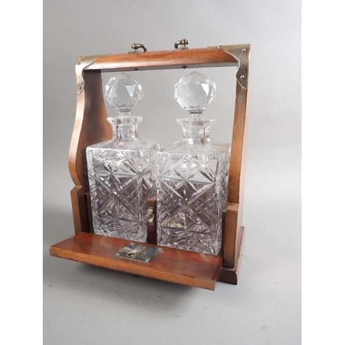 181 - An oak tantalus with two cut glass decanters and stoppers