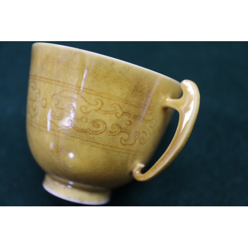 71 - A Chinese yellow glazed two-handled cup with incised beast decoration and six-character mark to base... 