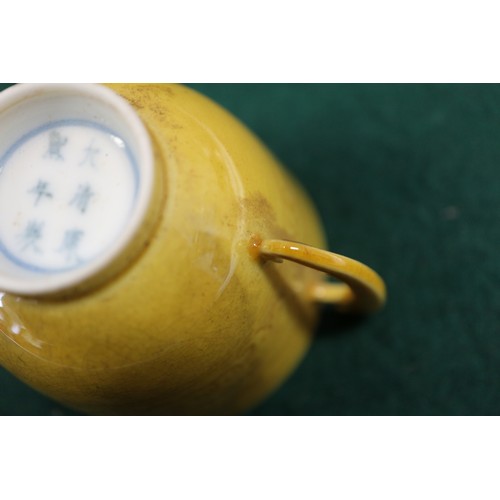 71 - A Chinese yellow glazed two-handled cup with incised beast decoration and six-character mark to base... 