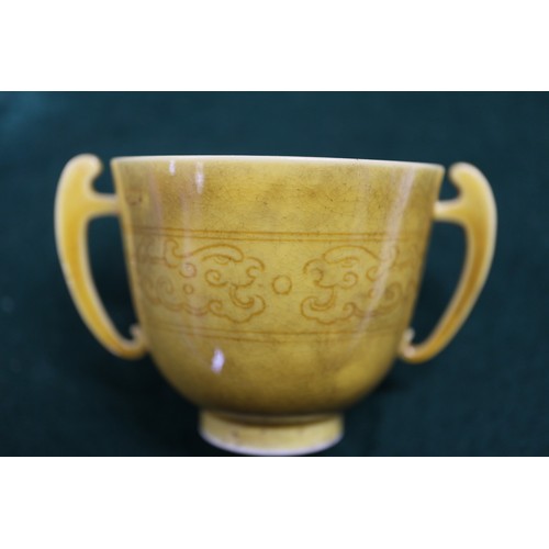 71 - A Chinese yellow glazed two-handled cup with incised beast decoration and six-character mark to base... 