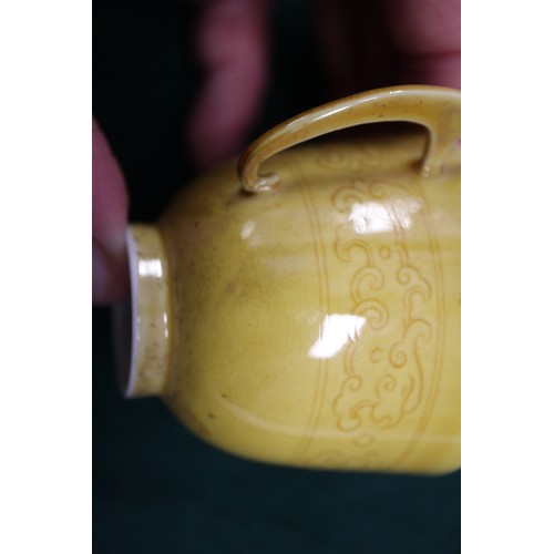 71 - A Chinese yellow glazed two-handled cup with incised beast decoration and six-character mark to base... 