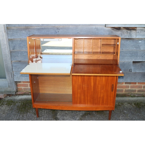 497 - A 1960s Doncraft teak desk/cocktail cabinet with two fall front compartments over one glass and one ... 