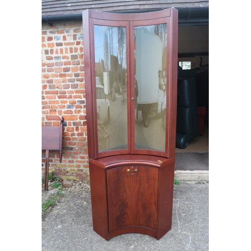 540 - A figured mahogany shape front corner cabinet, fitted central glazed door and two cupboards, 46