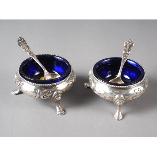 234 - A pair of Victorian silver cauldron salts with embossed decoration, blue glass liners and a pair of ... 