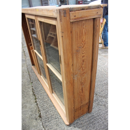 586 - A waxed pine bookcase enclosed three sliding glazed panel doors, 68