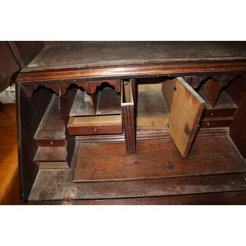 415 - An 18th century oak bureau bookcase, the upper section enclosed panelled doors over fitted writing c... 