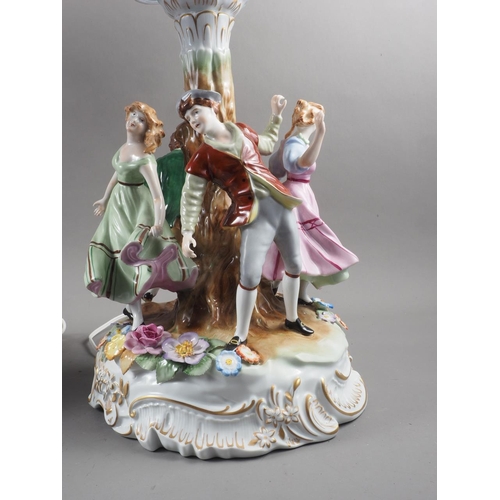 181 - A pair of Continental porcelain table lamps, the base decorated with figures dancing around a tree, ... 
