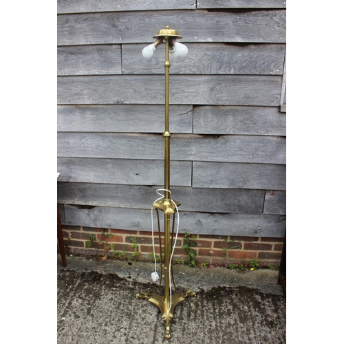 242 - A brass adjustable standard lamp, on triform base