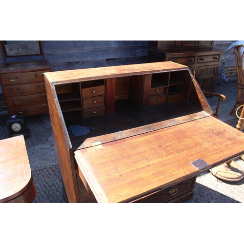 409 - A Georgian and later carved oak fall front bureau with fitted interior over four long drawers, on br... 