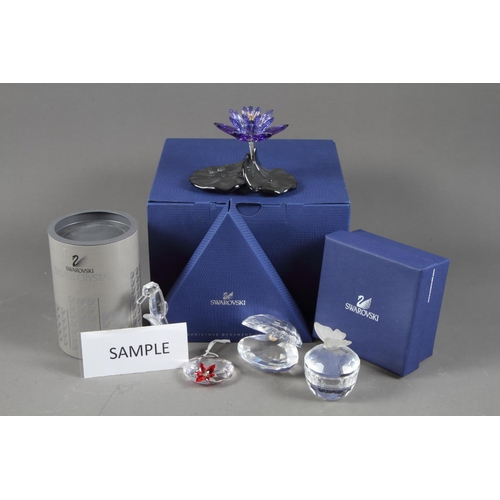 16 - A quantity of Swarovski ornaments, including a Waterlily candleholder, 4 1/2” wide, a blue violet wa... 