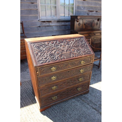 434 - A Georgian and later carved oak fall front bureau with fitted interior over four long drawers, on br... 