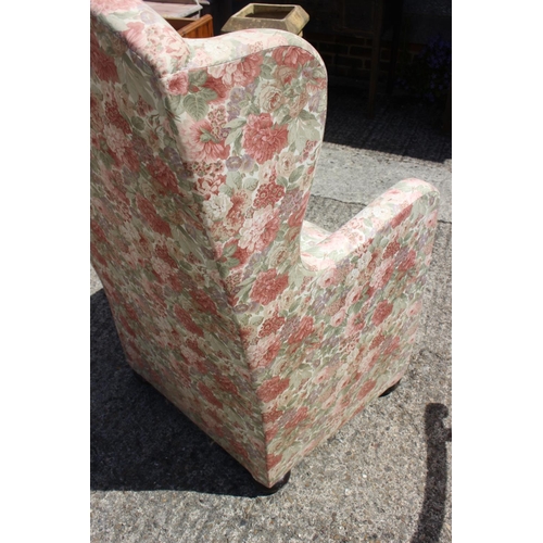 502 - A wing armchair, upholstered in a floral printed linen, on bun feet