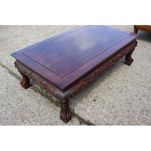 568 - A Chinese carved hardwood low table with dragon masks and paw feet, 47