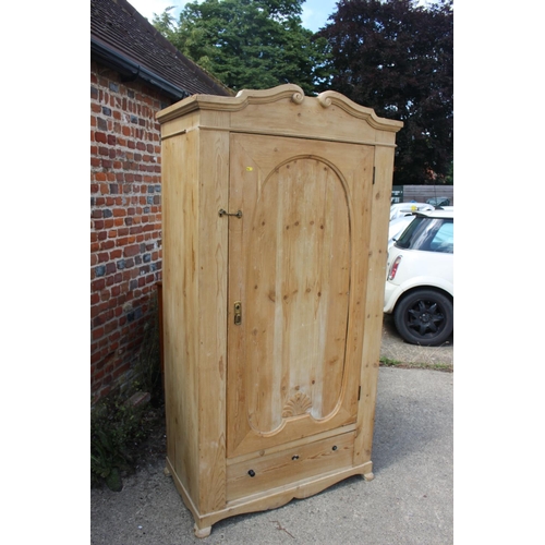 612 - A stripped pine wardrobe, fitted single door over one long drawer, on stile supports, 39