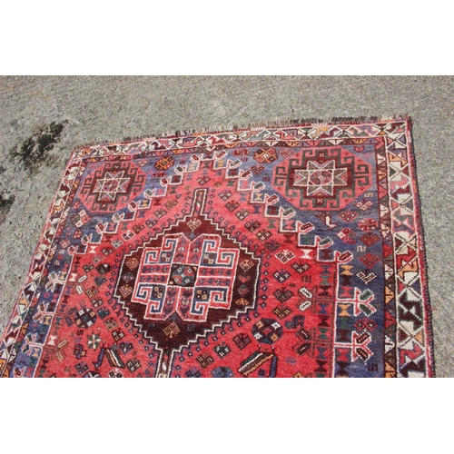 652 - A Qashqai design rug with three medallions on a bird and floral figured salmon ground and triple bor... 