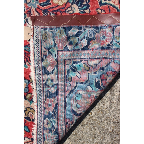 653 - A Persian rug with all-over floral design on a salmon ground and triple borders, 80