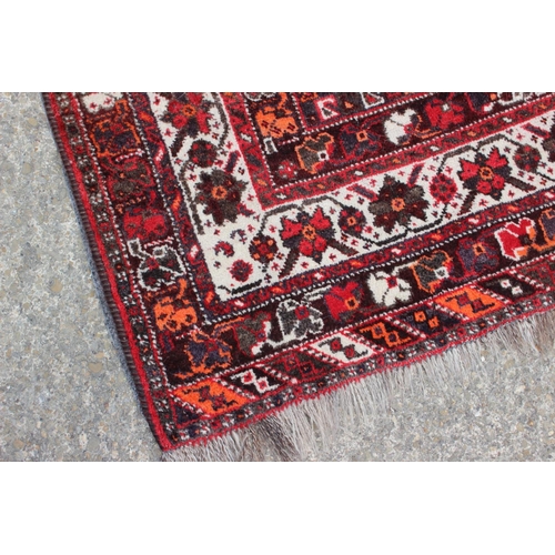 661 - A Qashqai design rug on a red ground and multi-bordered in shades of orange, green, red, black, brow... 