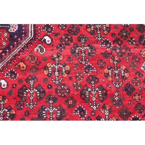 661 - A Qashqai design rug on a red ground and multi-bordered in shades of orange, green, red, black, brow... 