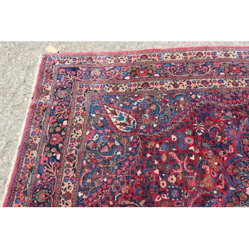 673 - A Kirman rug with all-over floral design and central white star medallion on a red ground and multi-... 