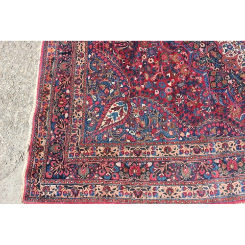 673 - A Kirman rug with all-over floral design and central white star medallion on a red ground and multi-... 