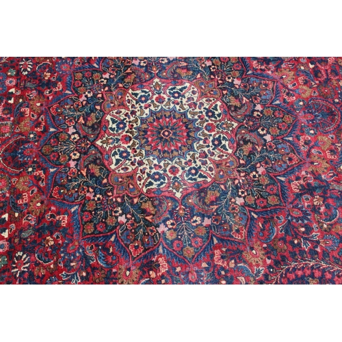 673 - A Kirman rug with all-over floral design and central white star medallion on a red ground and multi-... 