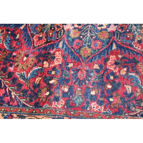 673 - A Kirman rug with all-over floral design and central white star medallion on a red ground and multi-... 