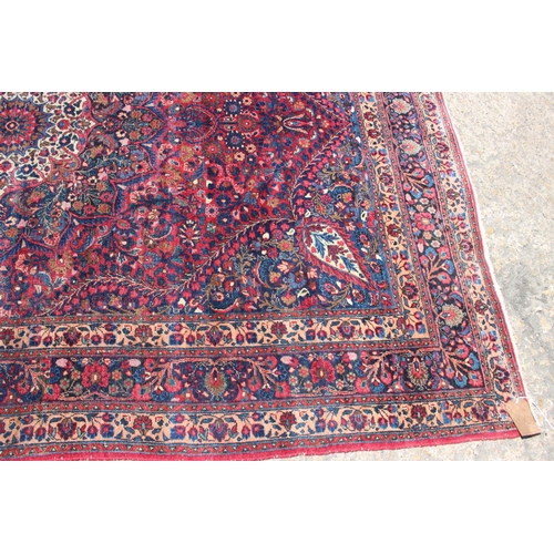 673 - A Kirman rug with all-over floral design and central white star medallion on a red ground and multi-... 