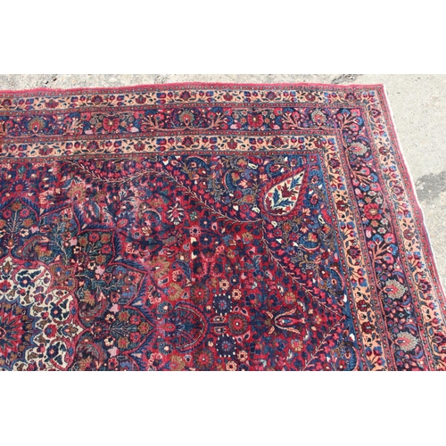 673 - A Kirman rug with all-over floral design and central white star medallion on a red ground and multi-... 