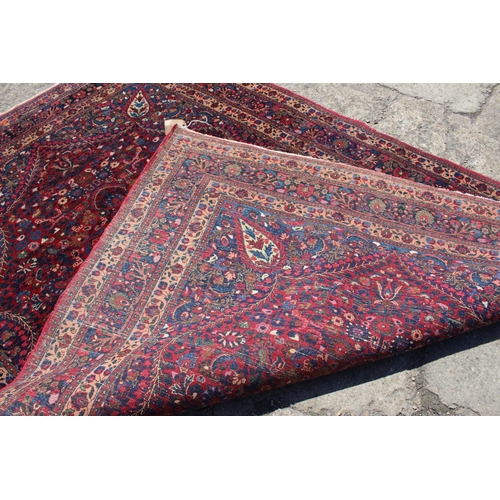 673 - A Kirman rug with all-over floral design and central white star medallion on a red ground and multi-... 